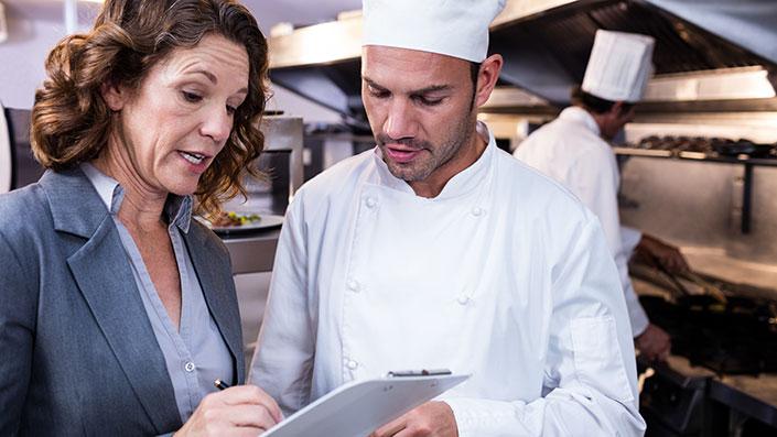 Environmental Health Officer (EHO) and chef reviewing health inspection results